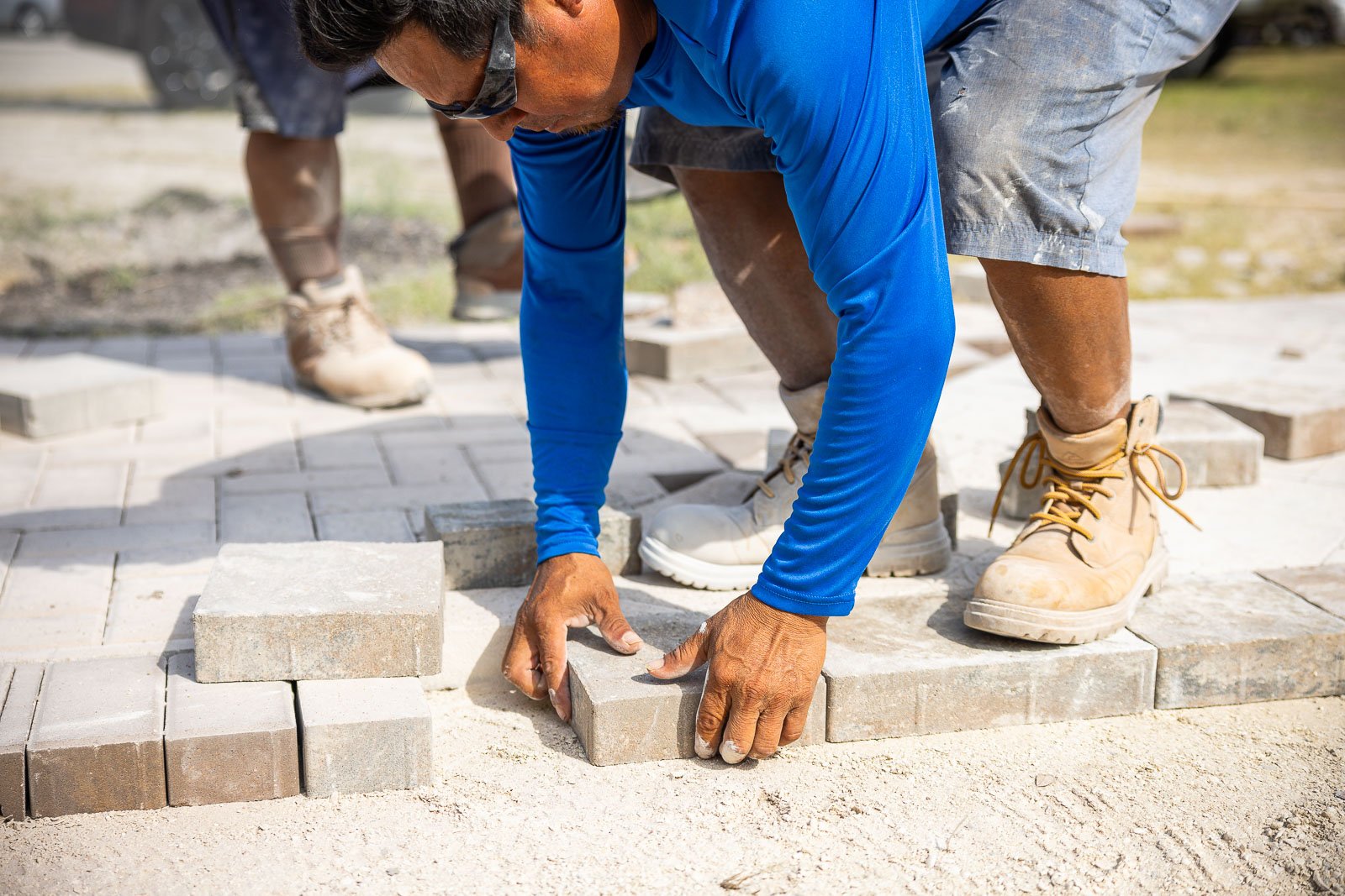 crew laying pavers for walkway 