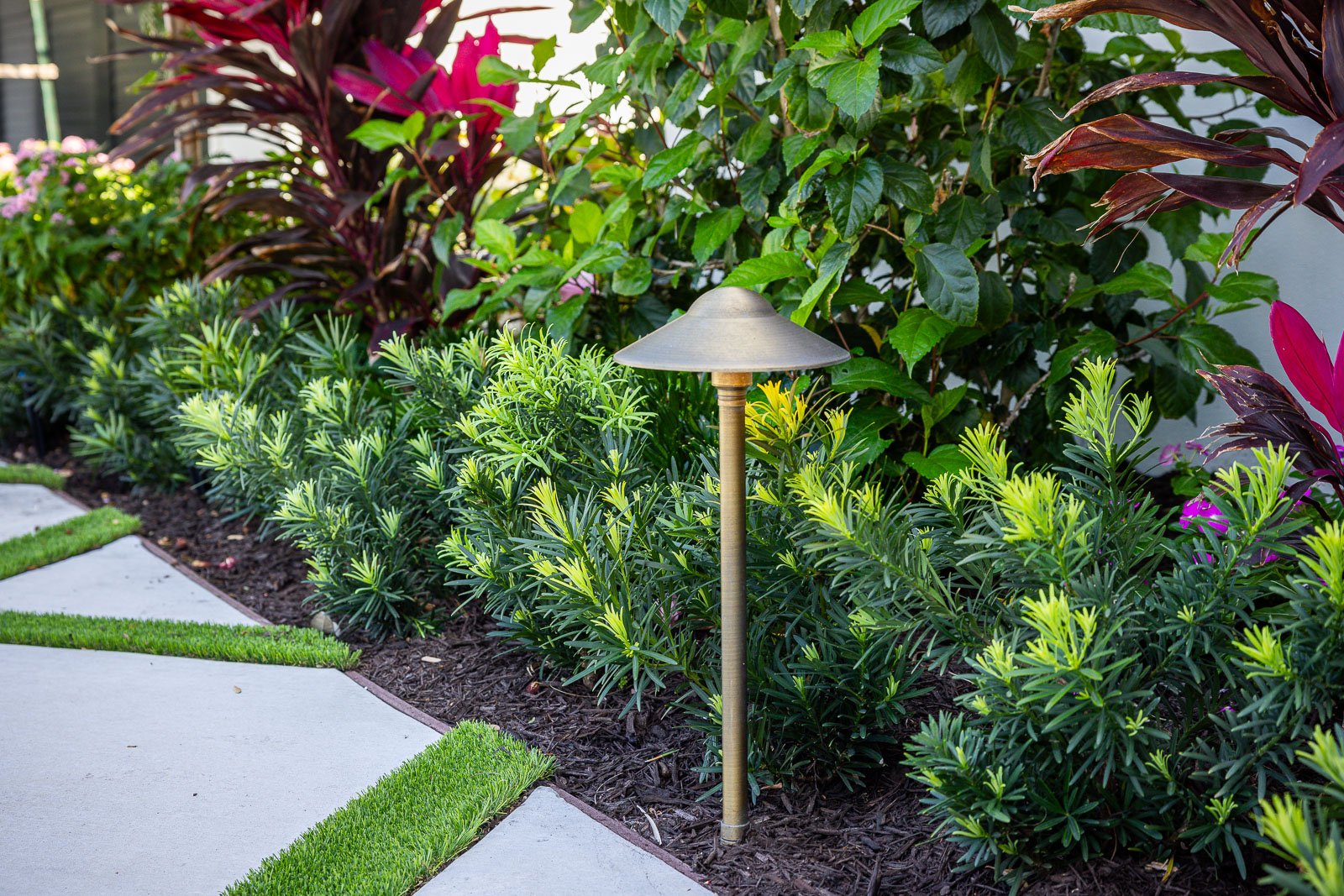 garden bed with mulch and plants along driveway 7