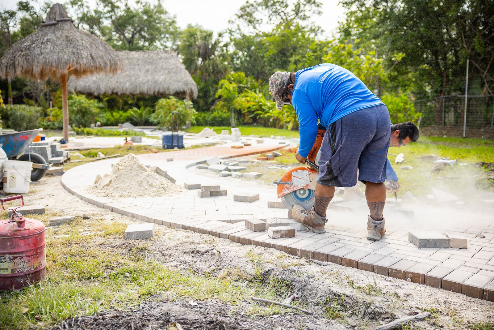 paver construction crew cutting bricks for walkway with tiki umbrella 