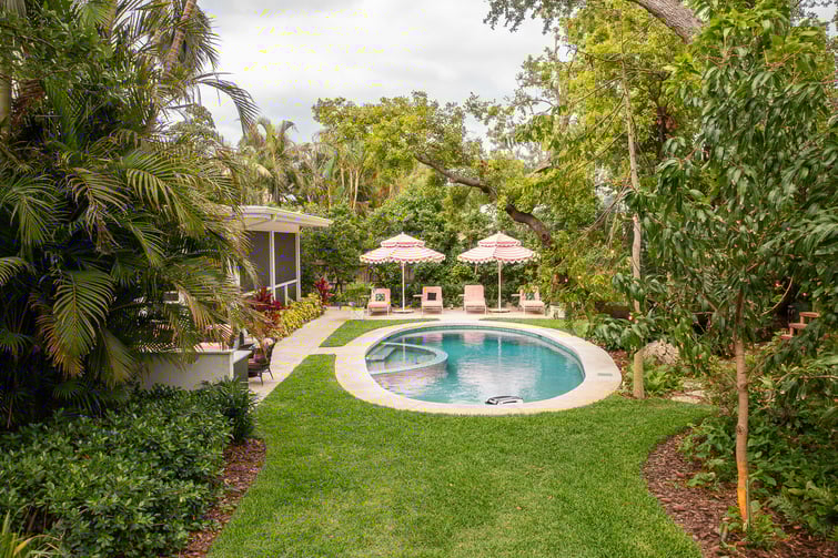 Backyard landscape in Sarasota with grass, small pool, and trees