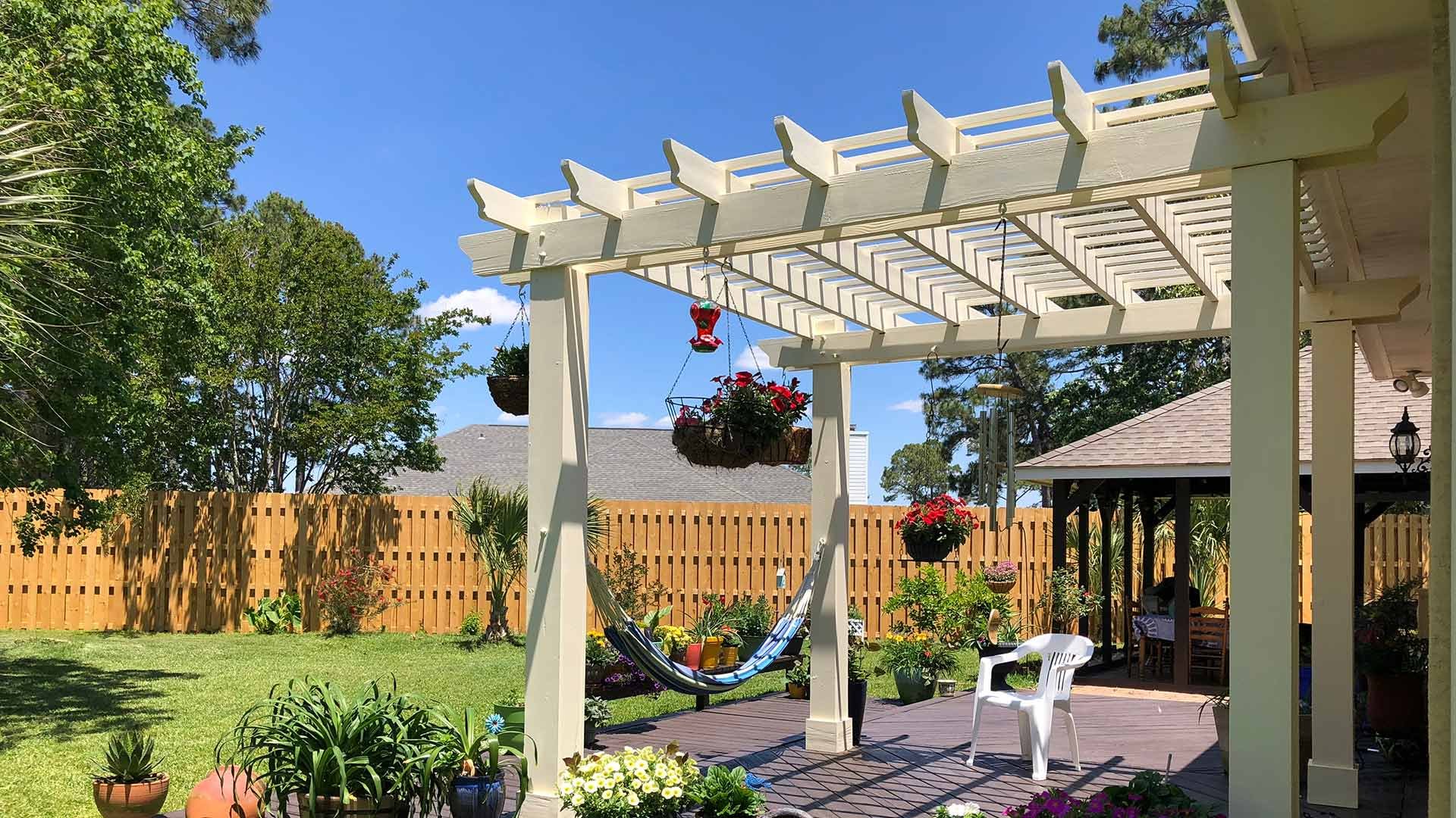 pergola in backyard with plants and deck