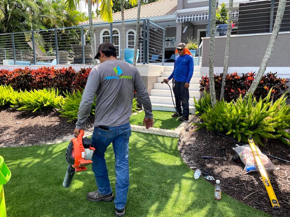 crew blowing off turf and watering plants 