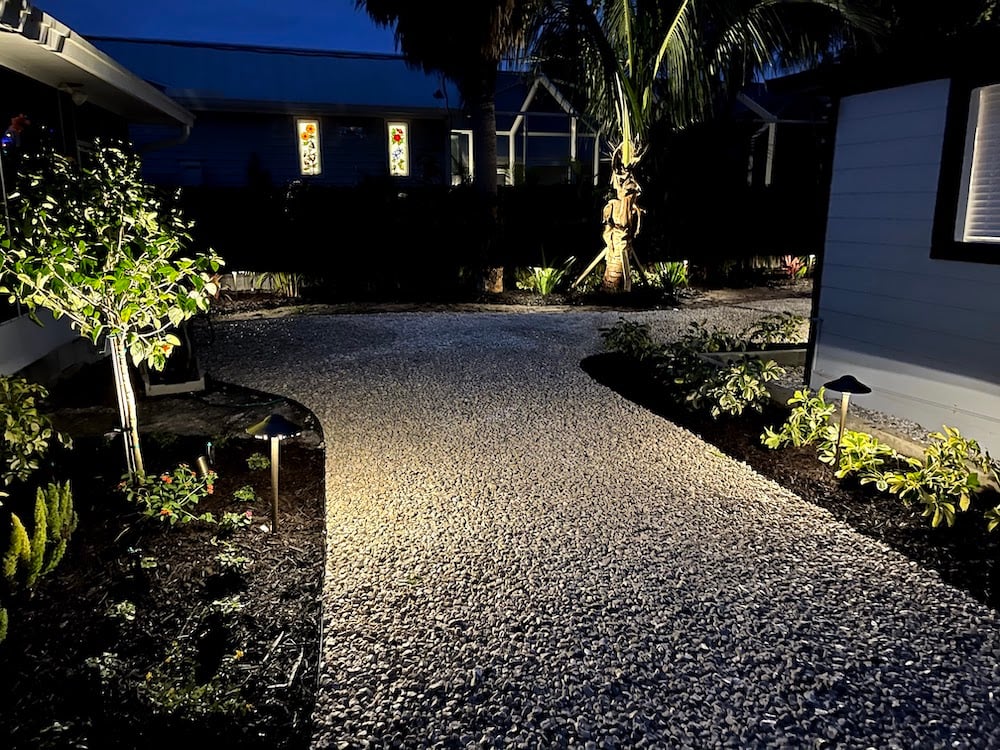 gravel walkway lit up with outdoor lighting at night