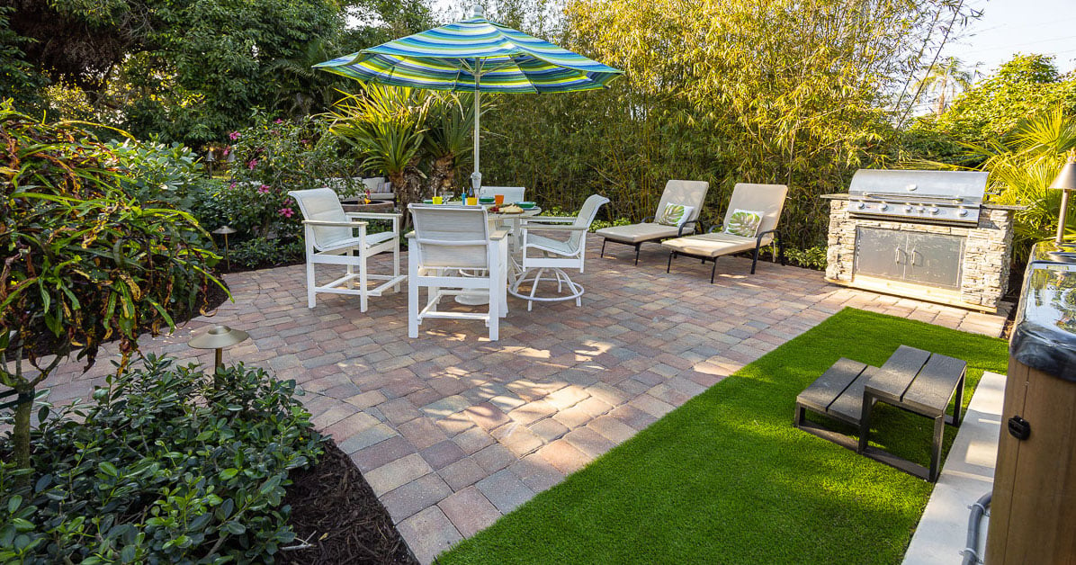 paver patio in backyard with table and chairs and grill