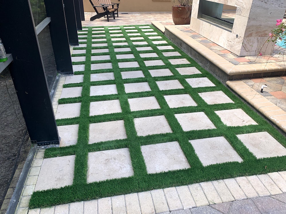 paver patio outlined by turf next to outdoor fireplace